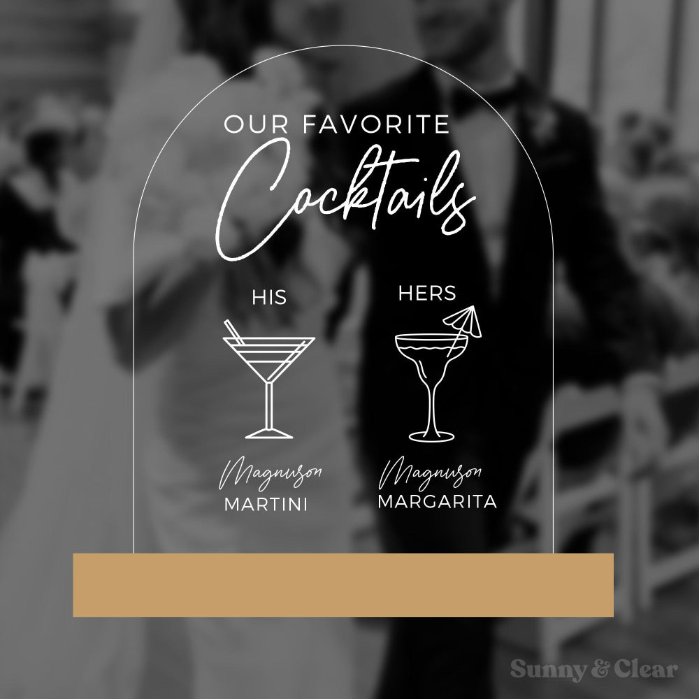 Acrylic sign with cocktail illustrations and text overlaying a blurred background of a couple.