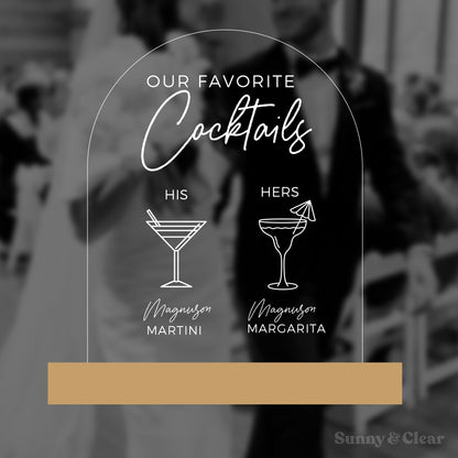Acrylic sign with cocktail illustrations and text overlaying a blurred background of a couple.