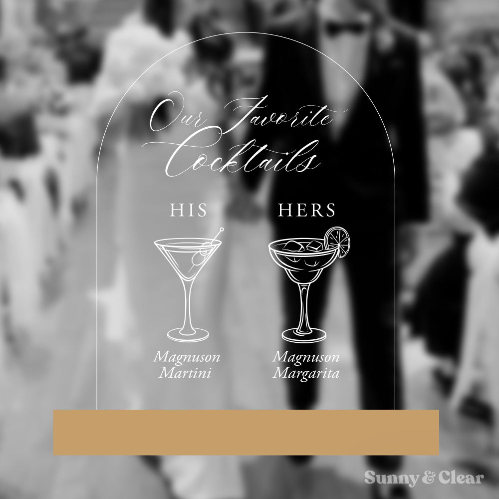 Decorative sign with cocktail illustrations and text 'Our Favorite Cocktails' on a blurred background.